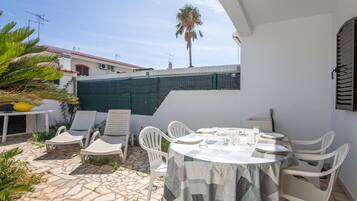 Un patio con una mesa y sillas, una palmera y un edificio al fondo.