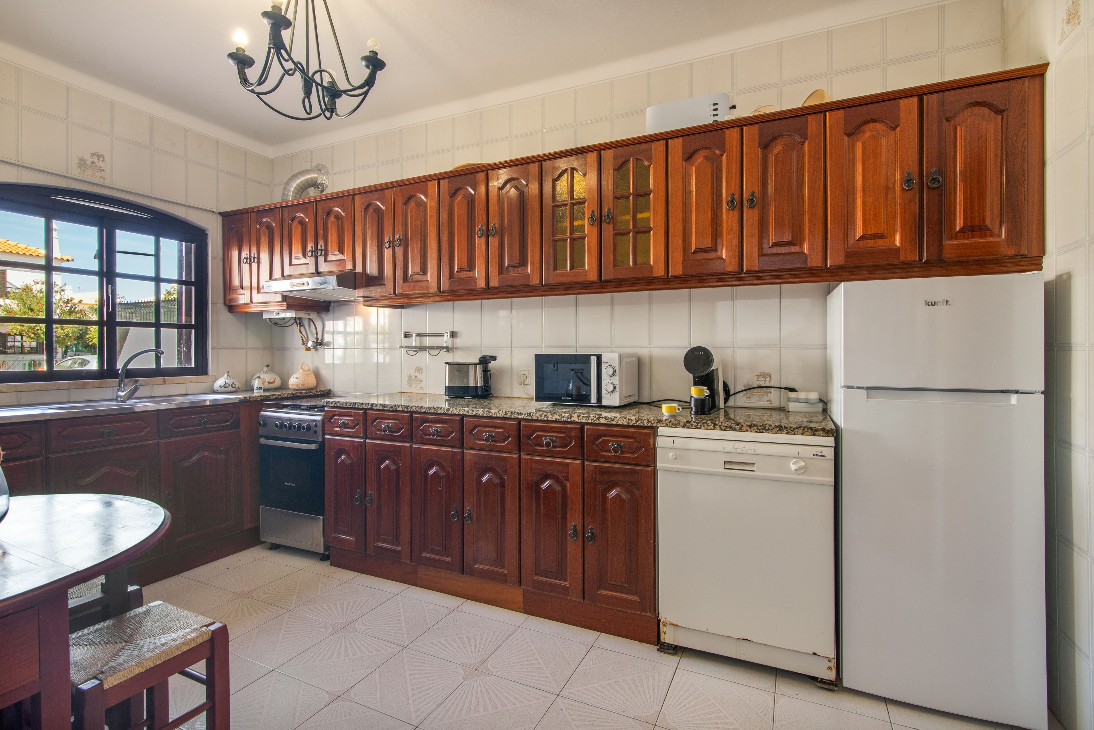 Una cocina con armarios de madera, estufa, microondas y refrigerador.
