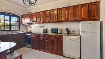 Una cocina con armarios de madera, estufa, microondas y refrigerador.