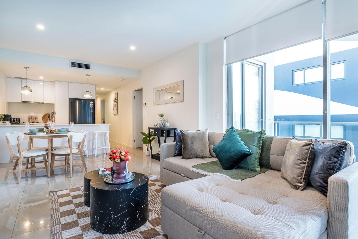 A modern living room with a sofa, a coffee table, and a dining area with chairs and a table.