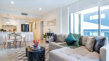 A modern living room with a sofa, a coffee table, and a dining area with chairs and a table.