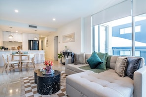 A modern living room with a sofa, a coffee table, and a dining area with chairs and a table. - Fantastic 3-bedroom apartment with AC in charming West End (West End)