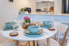 A dining table set with blue bowls, wine glasses, and wooden coasters. - Fantastic 3-bedroom apartment with AC in charming West End (West End)