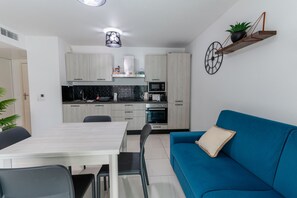 Une cuisine moderne avec un coin repas, un canapé bleu et une horloge murale.