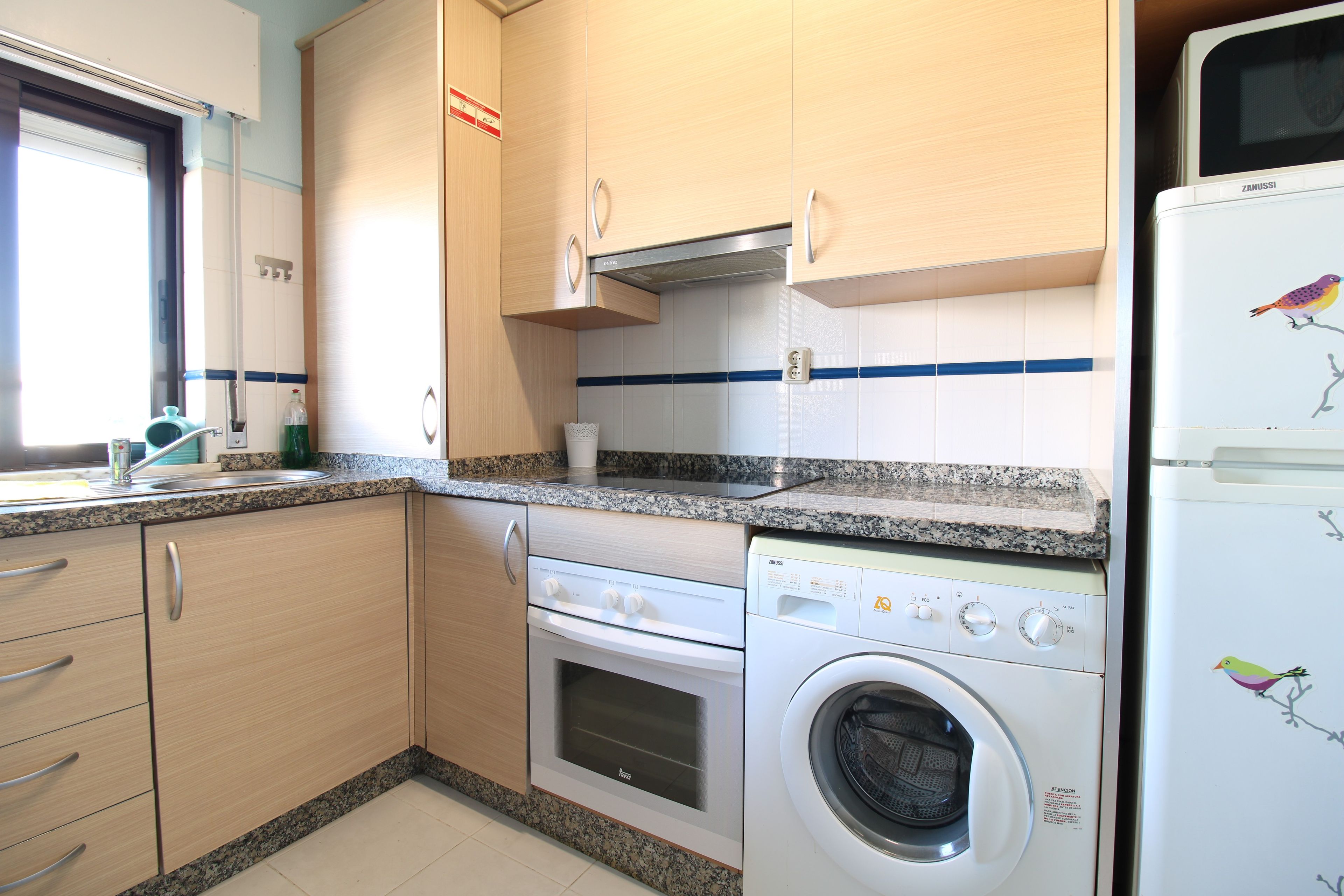Una cocina compacta con lavadora, microondas y estufa.