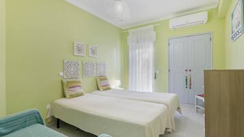 Una habitación con dos camas, un armario, una lámpara colgante y un aire acondicionado instalado en la pared.