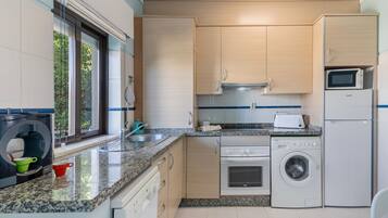 A modern kitchen with granite countertops, stainless steel appliances, and light wood cabinetry.