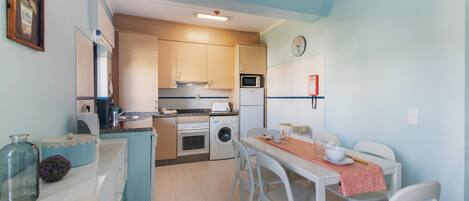 A compact kitchen with a dining area, a washing machine, and a microwave.