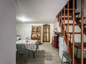 Cuina compacta amb un armari de fusta, una rentadora i zona de menjador amb taula i cadires.