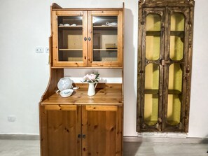 Un armari de fusta amb dues portes i una taula petita amb un ram i un bol.