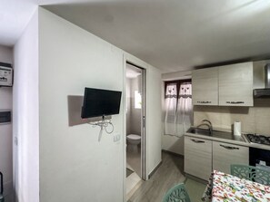 A compact kitchen with a television, a sink, and a stove. - The Lucretili's Shelters - Orazio's Land (Licenza)