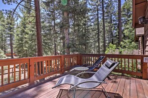 A wooden deck with two lounge chairs and a small table, surrounded by tall pine trees. - Spacious SLT Retreat w Forest Views (South Lake Tahoe)