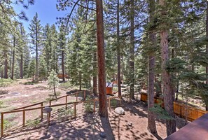 A forested area with a wooden fence, a small structure, and a clear sky. - Spacious SLT Retreat w Forest Views (South Lake Tahoe)