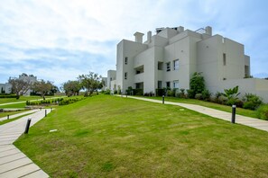 A modern building with a flat roof, rectangular windows, and a paved walkway leading to it. - EMERALD GREEN 2477 SAN ROQUE (San Roque)