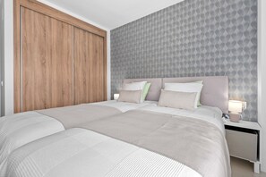 A bedroom with a large bed, two bedside tables, a nightstand, a wooden wardrobe, and a patterned wallpaper. - EMERALD GREEN 2477 SAN ROQUE (San Roque)