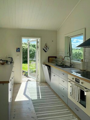 A kitchen with a large window, a sink, and a stove. - Forest home with sauna by Dalälven in Hedesunda (Hedesunda)