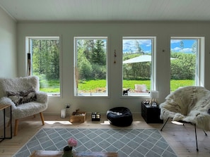 A room with three large windows, a fluffy chair, a bean bag, and a patterned rug. - Forest home with sauna by Dalälven in Hedesunda (Hedesunda)