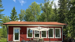 Um edifício vermelho com telhado telhado, grandes janelas e um pátio com mobiliário de exterior.