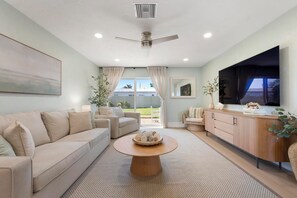 A modern living room with a sofa, coffee table, and a TV. - Private Beach • 3 Heated Pools • Ground Floor (Siesta Key)