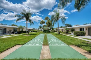 A shuffleboard court with a clear sky and palm trees. - Private Beach • 3 Heated Pools • Ground Floor (Siesta Key)