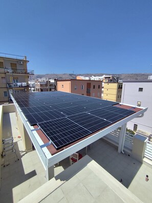 A rooftop with solar panels, a white railing, and a clear sky.