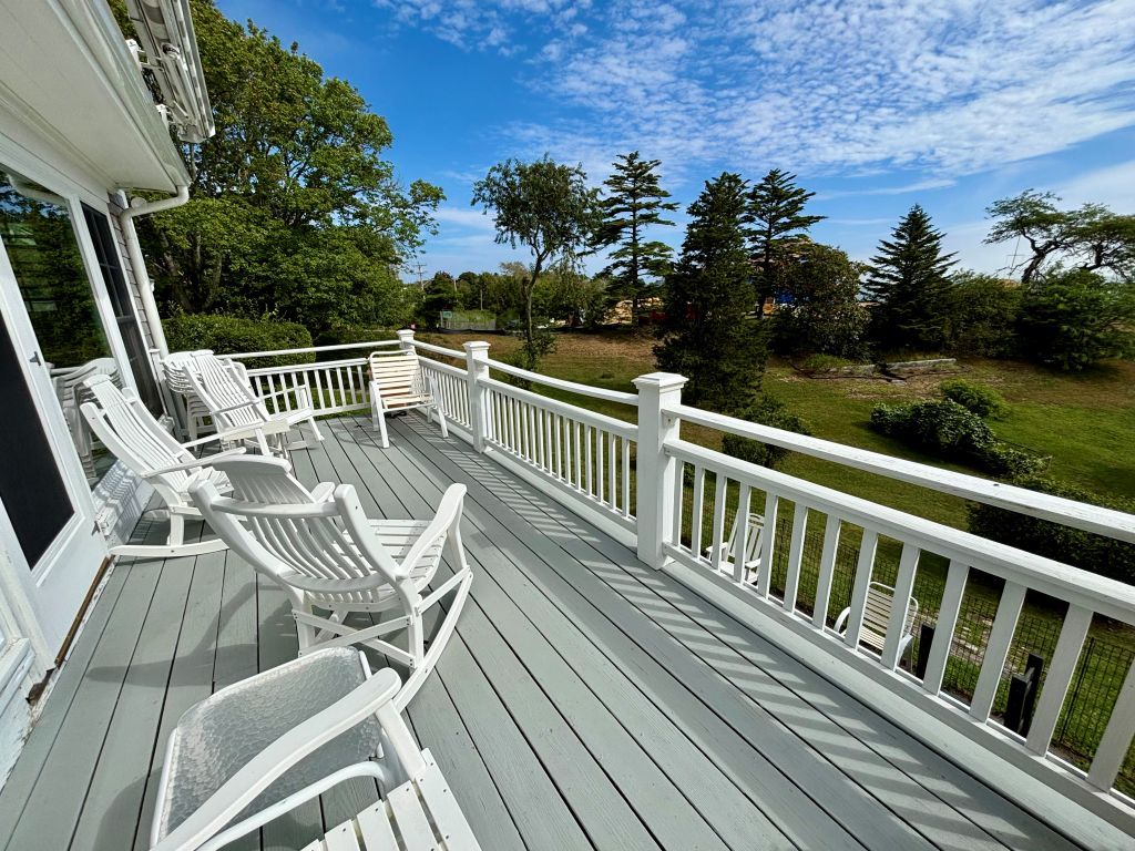 A wooden deck with white railings and outdoor furniture.
