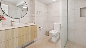 Ein modernes Badezimmer mit rundem Spiegel, Waschbecken, Toilette und Duschbereich.