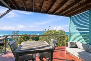 Eine Holzterrasse mit Tisch und Stühlen, die einen malerischen Meerblick bietet.