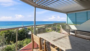 Eine Holterrasse mit Tisch und Stühlen mit Blick auf Strand und Meer.