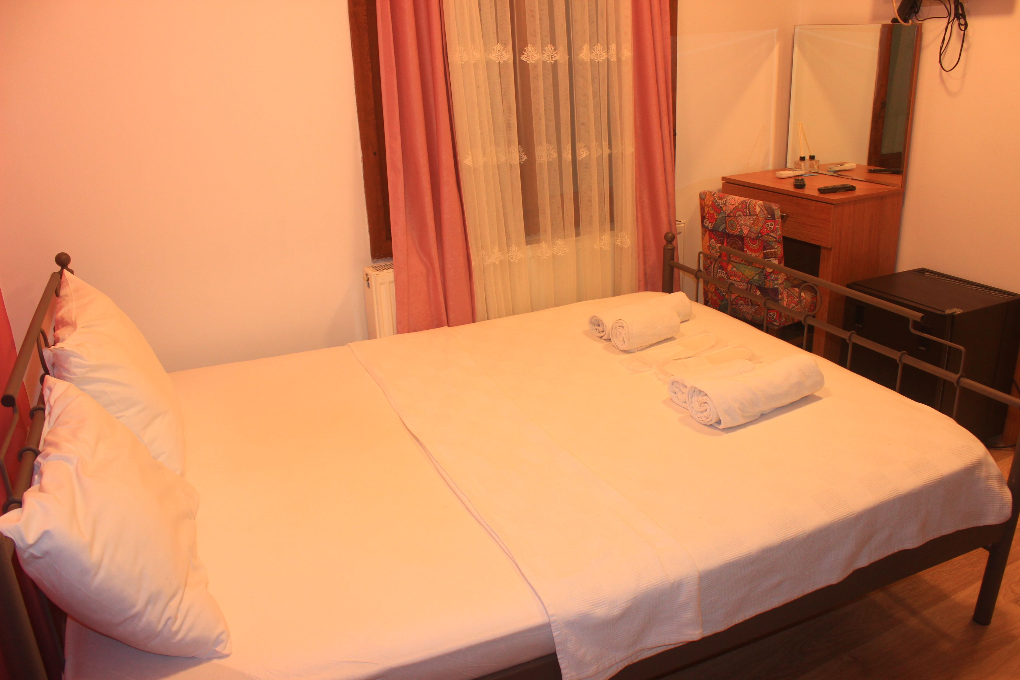 A bed with white linens, a wooden headboard, and two rolled towels.