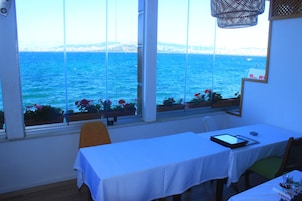 Una habitación con una mesa y sillas, vistas al mar y una ventana con vistas a la ciudad.