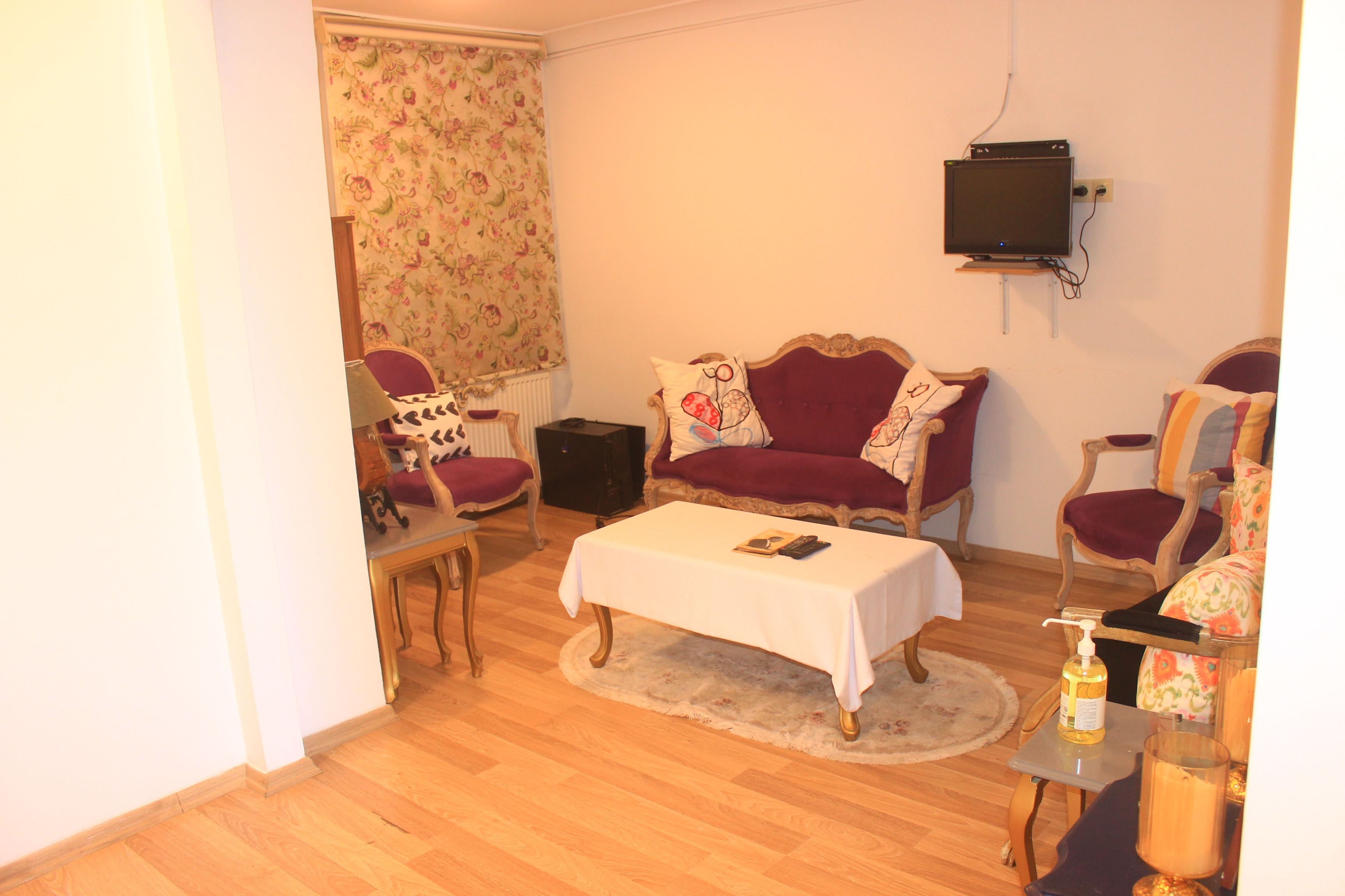 A living room with a sofa, armchairs, a coffee table, and a television mounted on the wall.