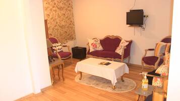 A living room with a sofa, armchairs, a coffee table, and a television mounted on the wall.