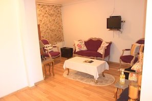 A living room with a sofa, armchairs, a coffee table, and a television mounted on the wall. - yeni kalamari  otel büyükada (Adalar)