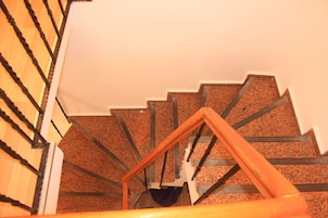 Una escalera en espiral con barandillas de madera y piso alfombrado.