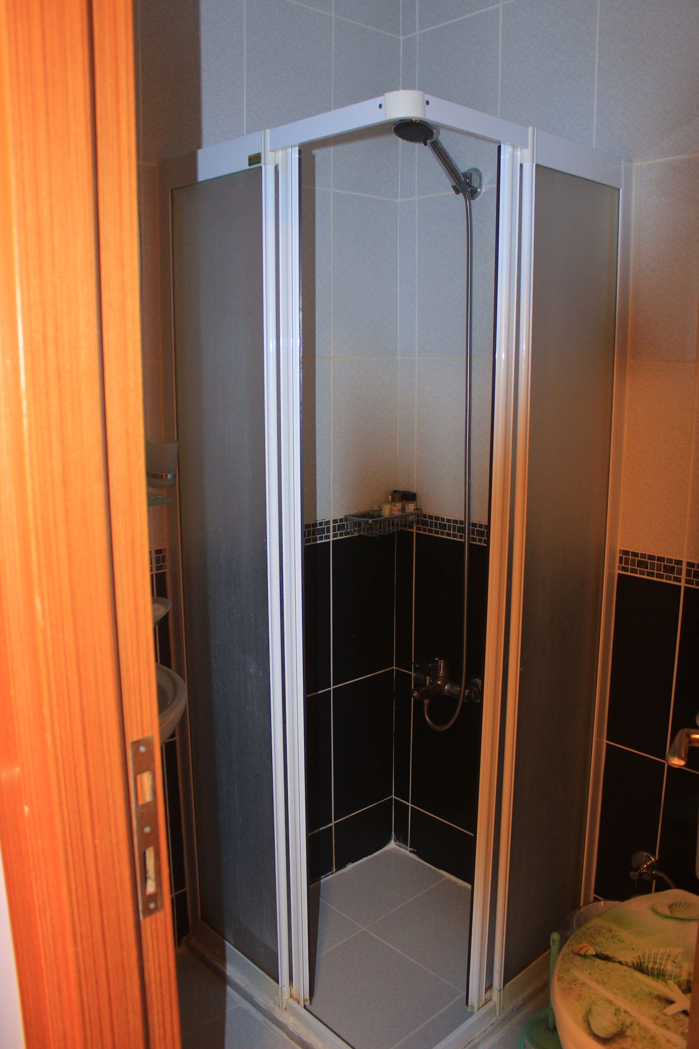 A bathroom with a shower stall, tiled walls, and a toilet.