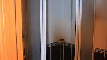 A bathroom with a shower stall, tiled walls, and a toilet.
