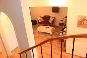 A staircase leading to a living room with a red sofa, a white table, and a painting on the wall. - yeni kalamari  otel büyükada (Adalar)