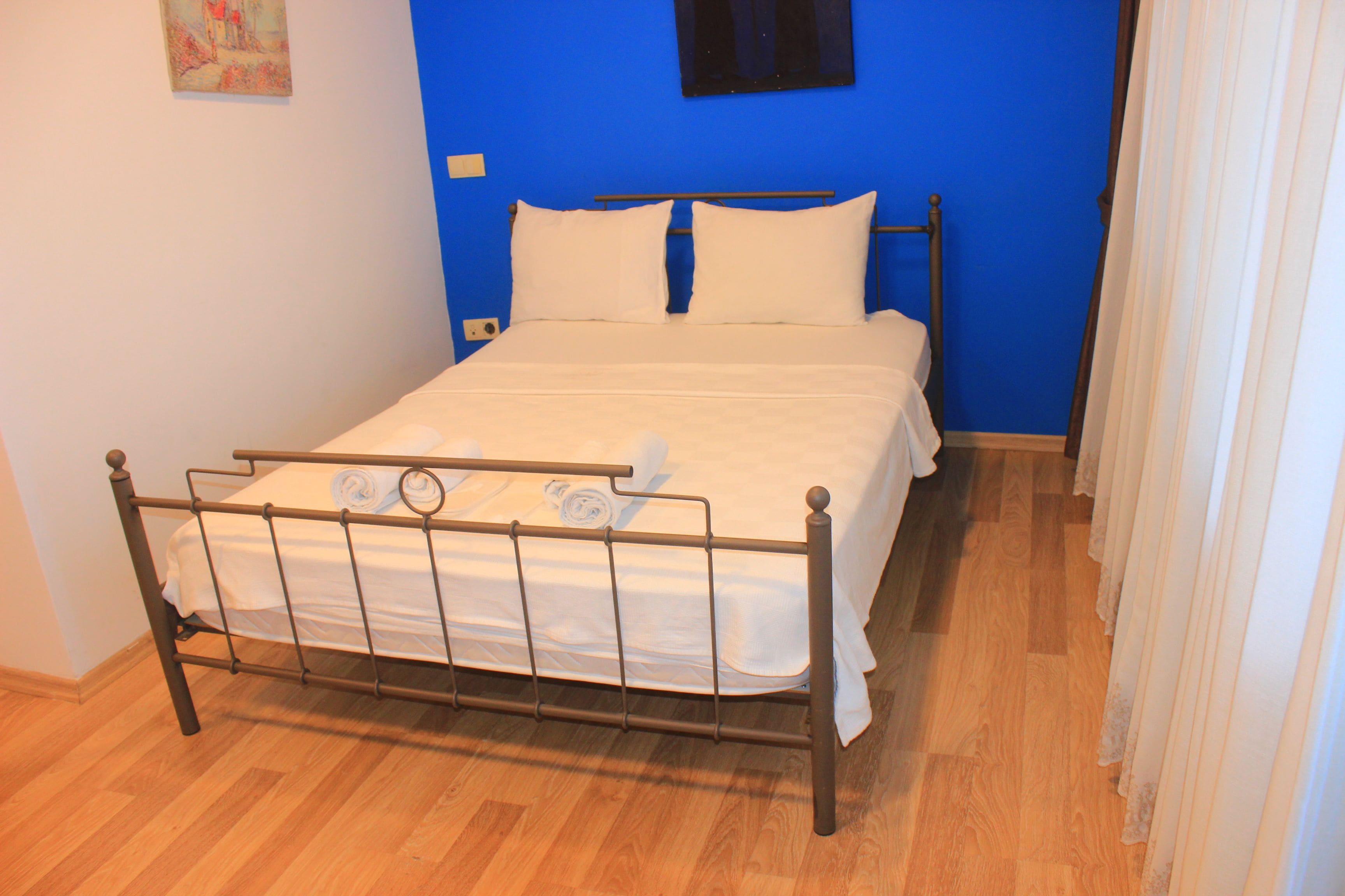 Una cama en una habitación con paredes azules y suelo de madera.