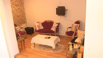 A living room with a sofa, armchairs, a coffee table, and a television.