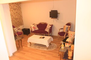 Una sala de estar con un sofá, sillones, una mesa de centro y un televisor.