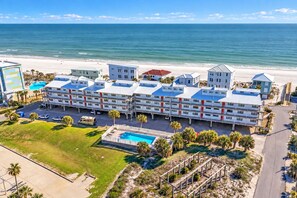 Hotel na praia com vários edifícios, piscina e vista para o mar.
