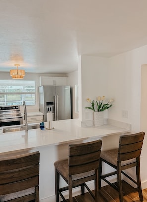A kitchen with a central island, stainless steel appliances, and a window providing a view. - Punta Gorda Waterfront Escape, Private Pool, Gulf Access, 3BR, Near Downtown (Punta Gorda)