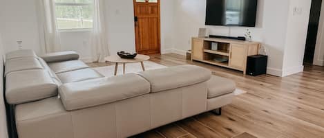 A modern living room with a sectional sofa, a flat-screen TV, and a wooden entertainment unit.