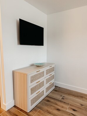 A room with a flat-screen TV mounted on the wall, a light-colored wooden cabinet with drawers, and a wooden floor. - Punta Gorda Waterfront Escape, Private Pool, Gulf Access, 3BR, Near Downtown (Punta Gorda)