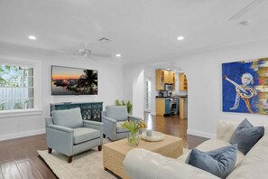 A spacious living room with a sofa, armchairs, and a coffee table. A kitchen is visible in the background with modern appliances. - Tropical Hideaway - Private Pool (Key West)