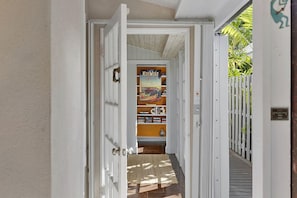 A hallway with a door leading to a room containing a bookshelf and a poster. - Tropical Hideaway - Private Pool (Key West)