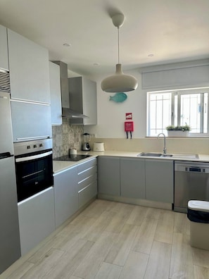 A modern kitchen with a built-in oven, a dishwasher, and a window with a view. - House of Saint Lucy! With a View of the Ria Formosa! (Santa Luzia)
