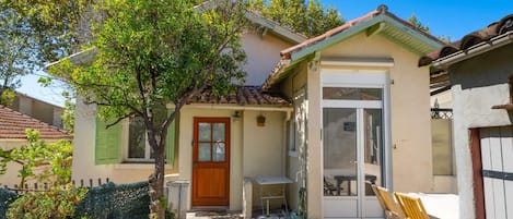 A house with a tiled roof, a wooden door, and a small patio with a table and chairs.