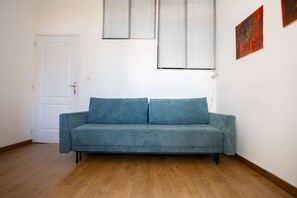 Ein Zimmer mit einem blauen Sofa, einer weißen Tür und einem Gemälde an der Wand.